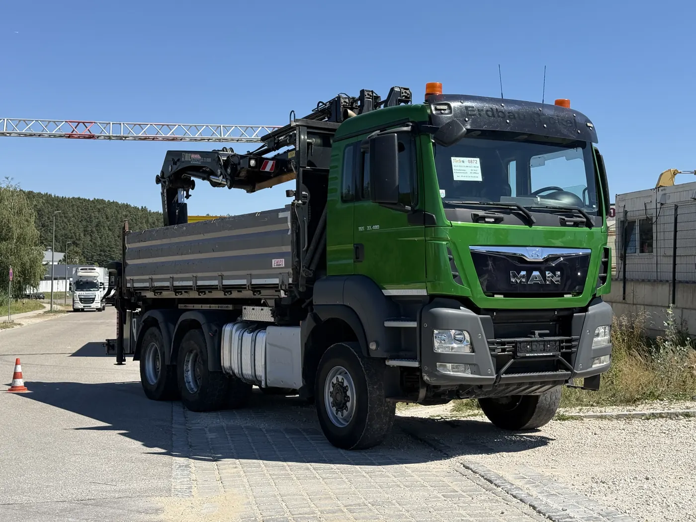 Grüner MAN Kran-LKW mit Pritsche